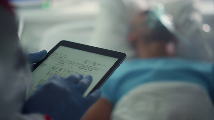 Doctor holding tablet screen checking patient medical history in ward closeup.
