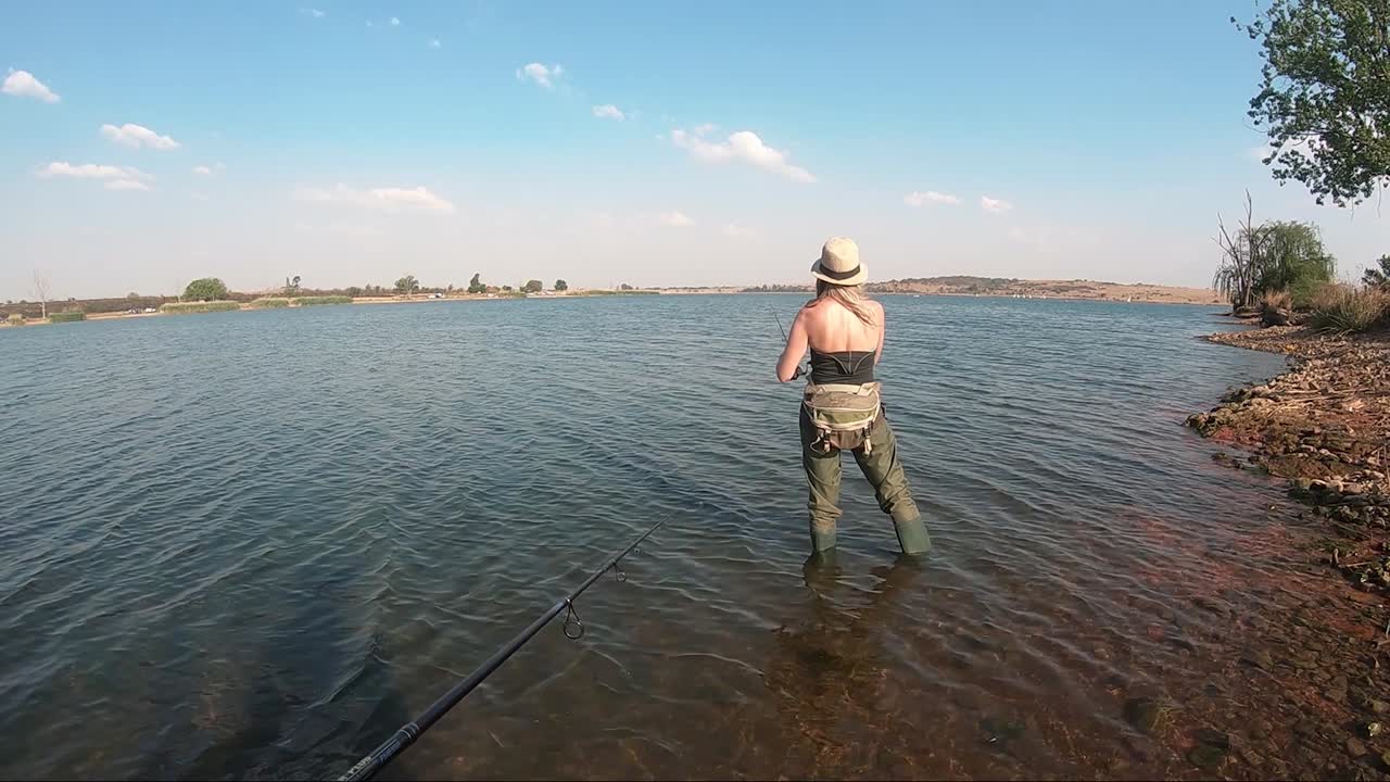 Chica hermosa pescando en un lago tranquilo en un día soleado en Sudáfrica.
