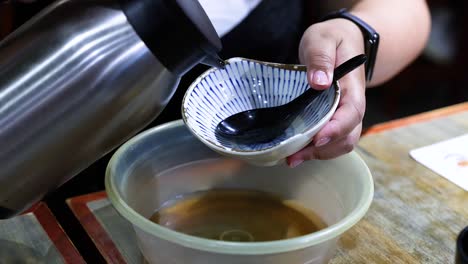 person pours water from thermos into bowl