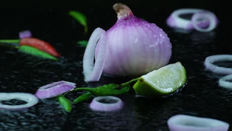 water surface rippling slow motion around organic green red chilli and sliced lime isolated on black background