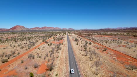 4k drone video following a camper van as it drives down a very long and straight road in the australian outback in northern territory