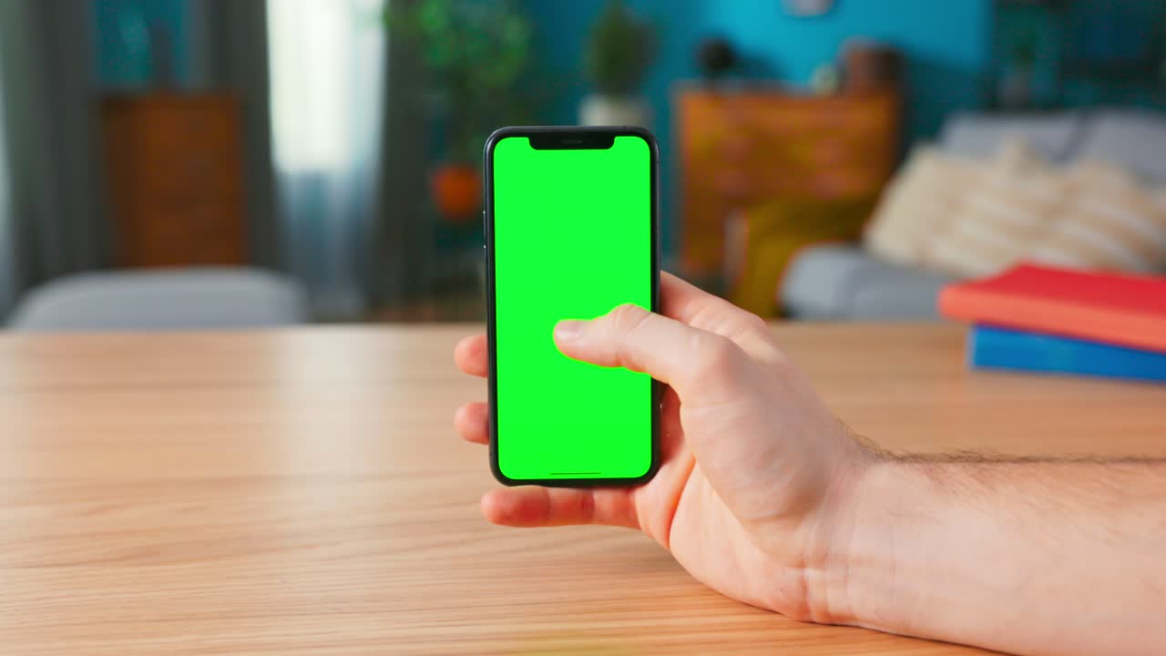 Close-up of a Man Holding and Making Hand Gestures on a Modern Green Mock-up Screen Smartphone. Touching Mobile Phone Chroma Key Screen with a Finger. Man clicks one time