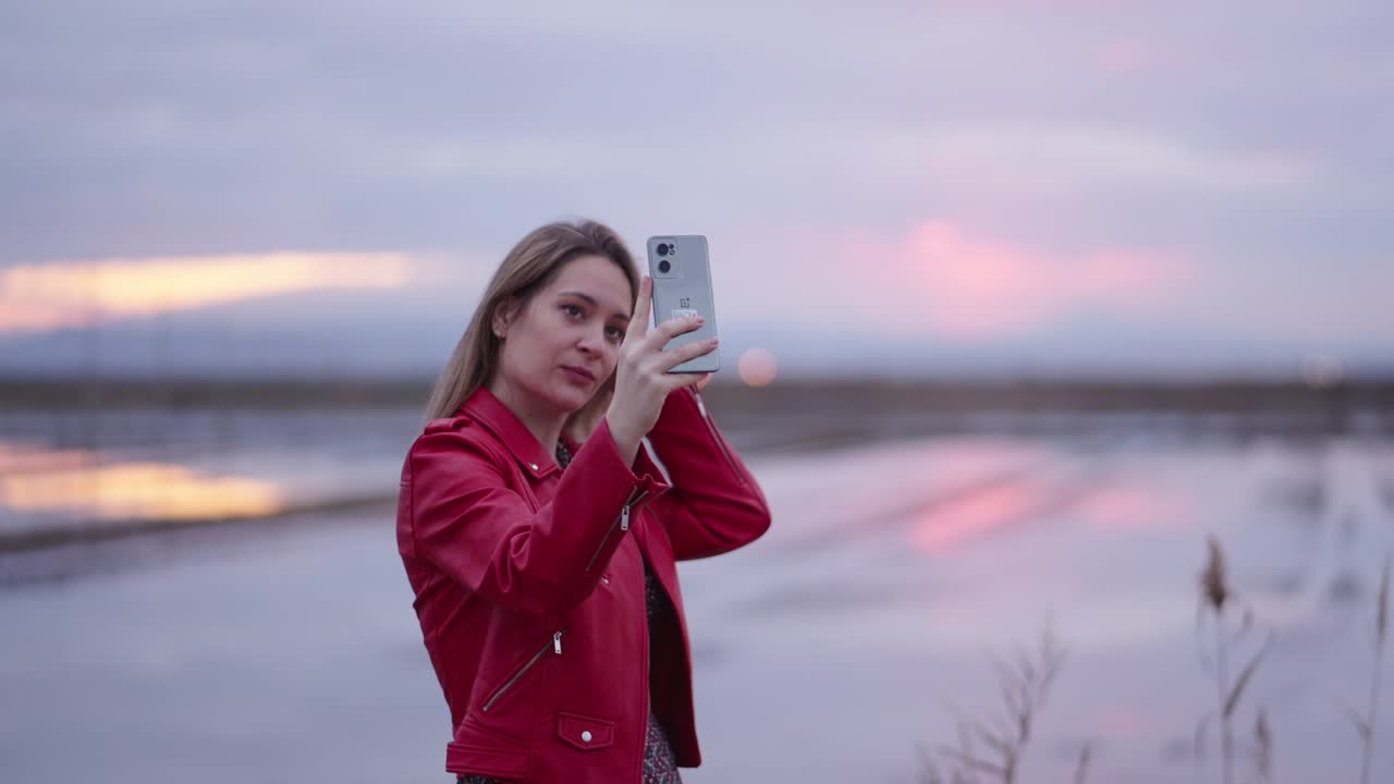 Woman using phone outdoors at sunset