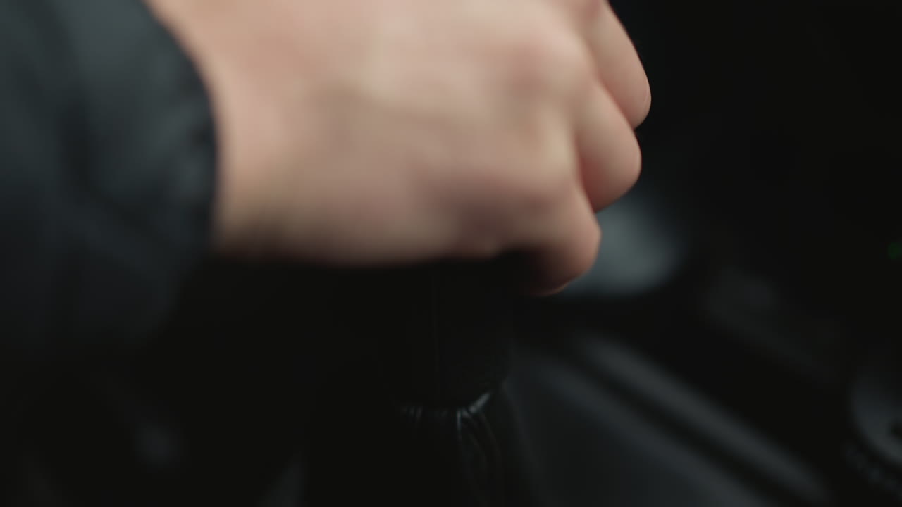 Close up of motorist shifting gear lever forward while driving with wrist and knuckle motion guiding stick with precise tactile control, showcasing mechanical precision and driver expertise