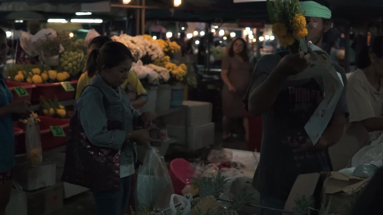 Merchant wrapping flowers for customer in market, Krabi, Thailand