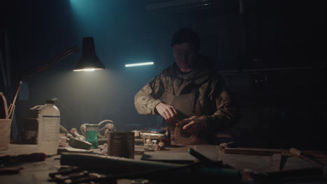 a bombmaker assembles a bomb in his workshop at night