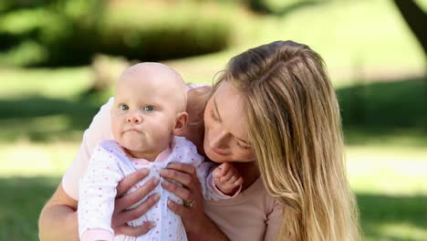 Madre-Feliz-Sosteniendo-A-Su-Bebé-En-El-Parque