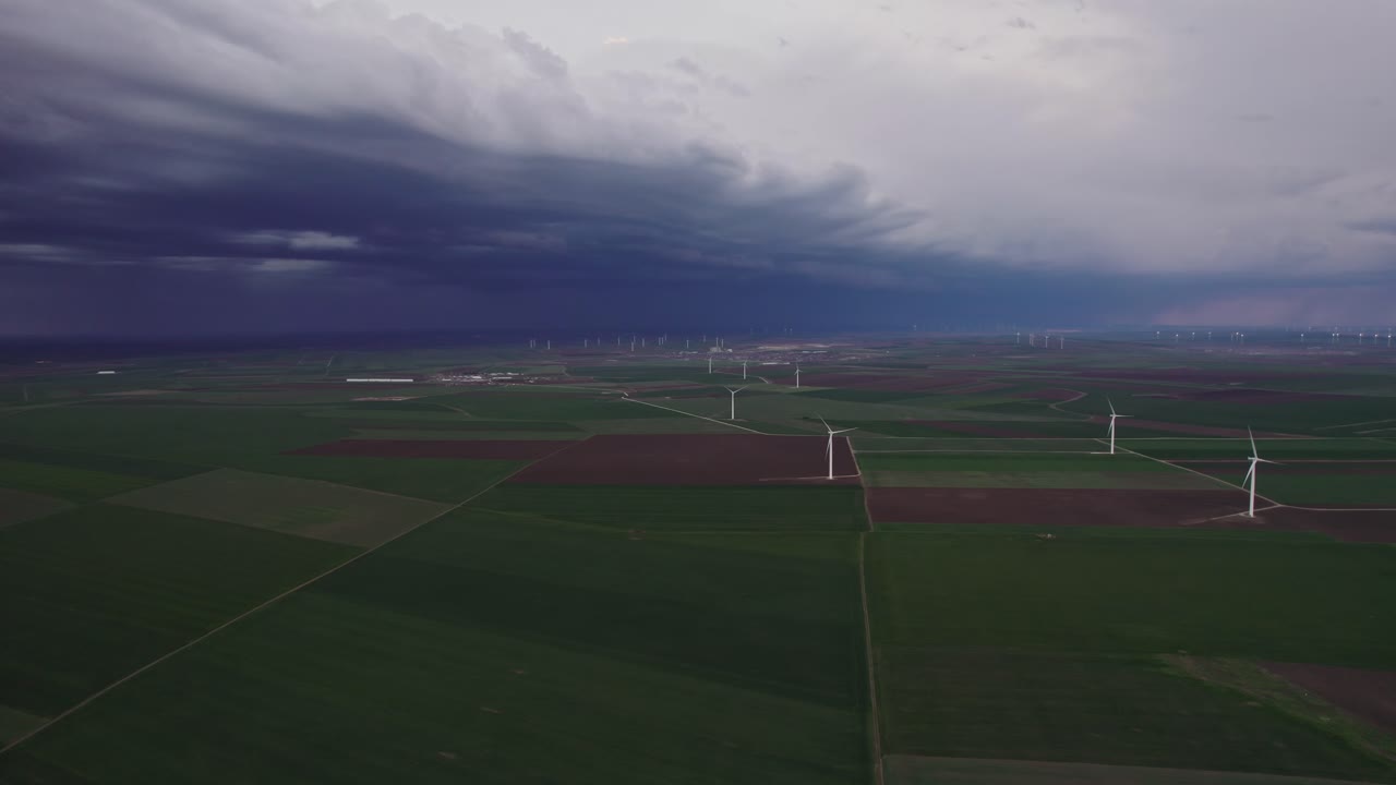 거대한 푸른 에 풍력 터빈은 극적인 폭풍 하늘 아래 멀리 어두운 구름과 함께