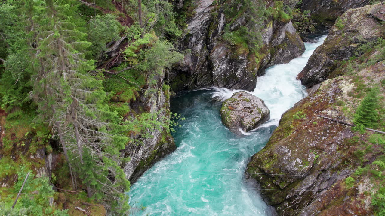 vista aérea, rápidos de agua blanca corriendo entre las paredes de un barranco escarpado y cubierto de musgo