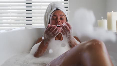 African-american-woman-blowing-soap-bubbles-in-the-bath-tub-in-the-bathroom-at-home