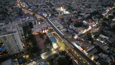 the city's metro train stops at the metro rail station, traffic streets and apartment buildings, as seen in this evening aerial view of chennai city's busy vadapalani signal neighborhood