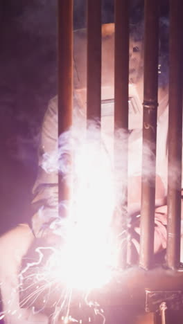 employee welds steel pipeline grid for boiler room with flame in workshop slow motion. professional worker connects metal tubes at metalworking plant