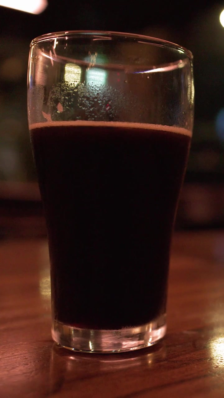 Ahşap bir masa üzerinde bardakta koyu stout biranın sabit orta çekimi