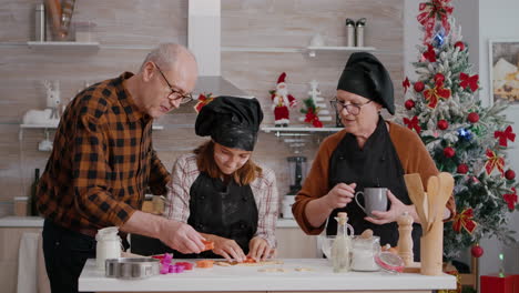 Grandparents-helping-grandchild-preparing-homemade-gingerbread-using-cookies-shape