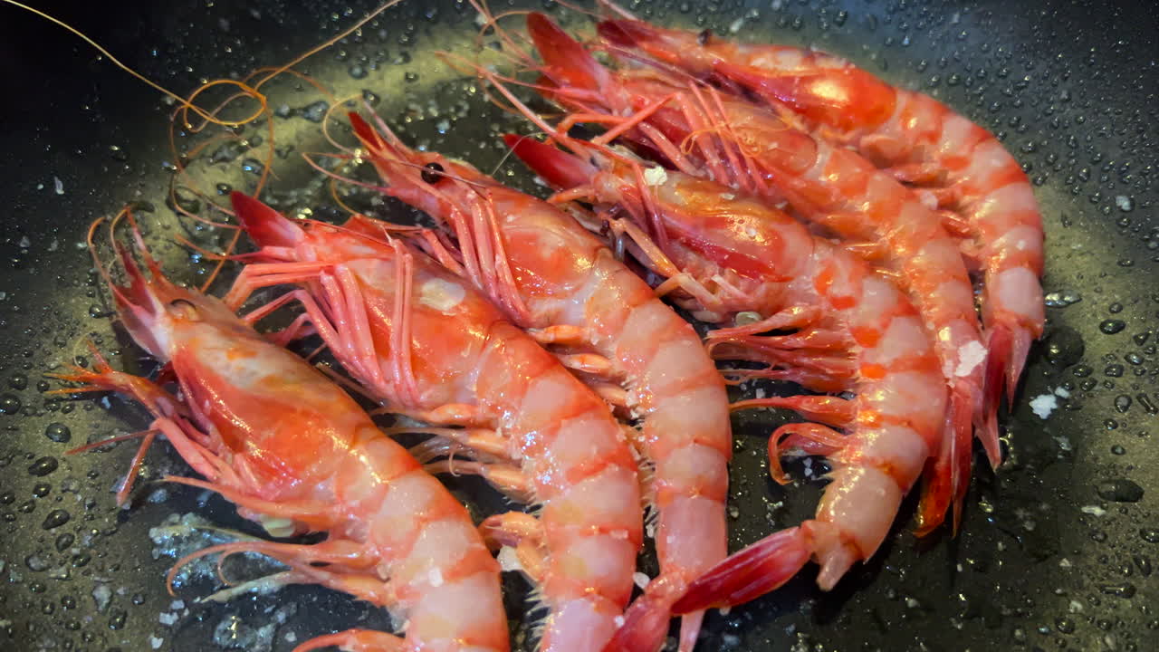 Frying fresh shrimps in a hot sizzling pan, cooking fresh catch seafood, 4K shot