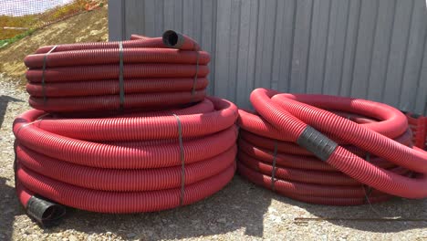 close up: two large coils of plastic conduits lay near a busy construction site.