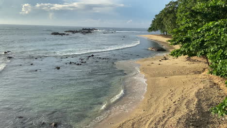 establishing static handheld shot of sandy beach in sri lanka at golden hour with small waves