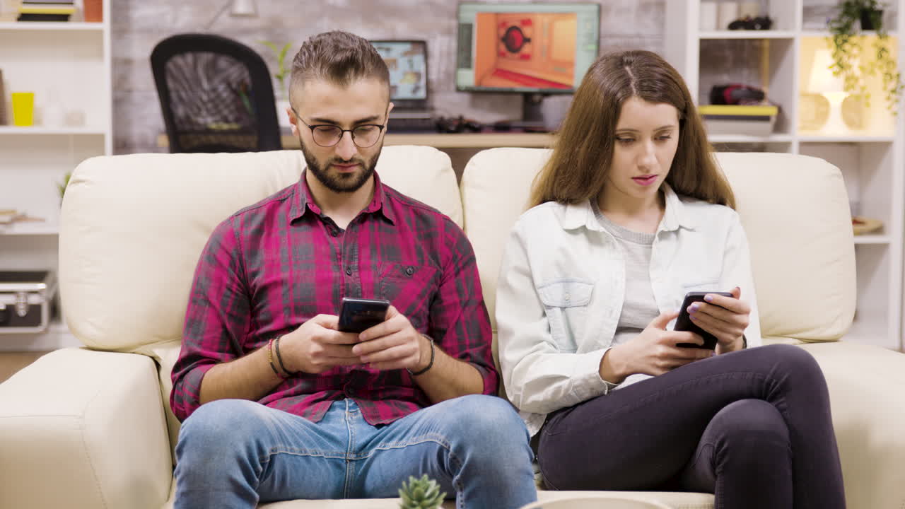 Couple Using Smartphones on Couch at Home