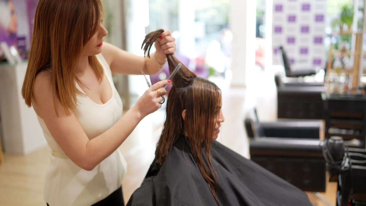 Parrucchiere professionista che taglia i capelli a un cliente in salone