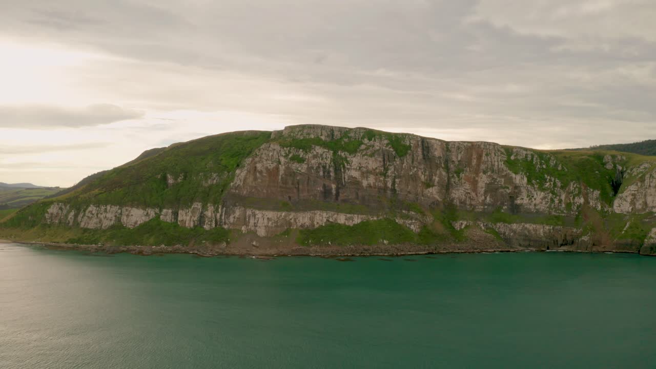 일몰 동안 뉴질랜드의 해안선을 따라 절벽의 왼쪽에서 오른쪽으로 천천히 궤도를 도는 공중 샷