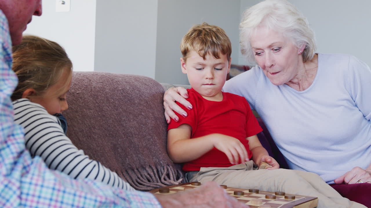 Nonni che giocano a dama con i nipoti a casa