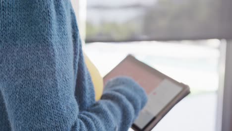 video of asian woman standing by window using tablet at home