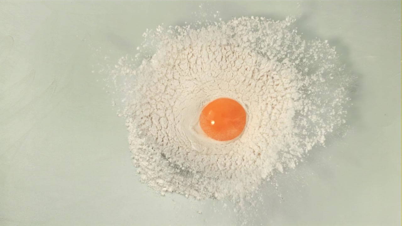 Fresh Egg Yolk Falling into White Flour, Top View