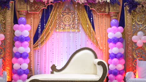 decoration of balloons around white sofa couch in center of stage ceremony wedding party birthday