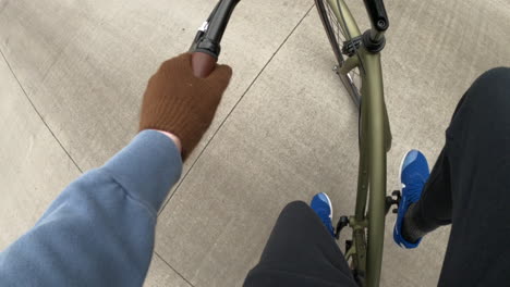 First-person-point-of-view-of-man-riding-green-bicycle-in-the-winter-with-blue-shoes