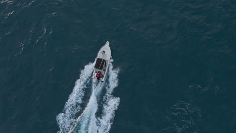 speedboat cruising on deep blue sea off genoa coast, aerial view, daytime