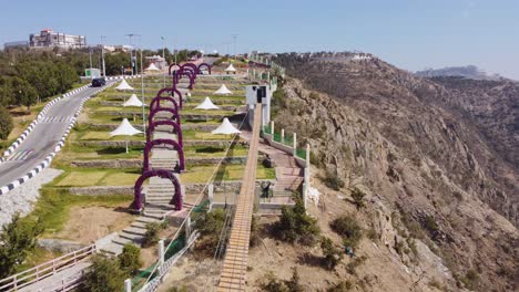 aerial drone view over a suspension bridge, towards the top of raghadan forest park, in saudi arabia