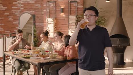 un joven bebiendo cerveza en una cena