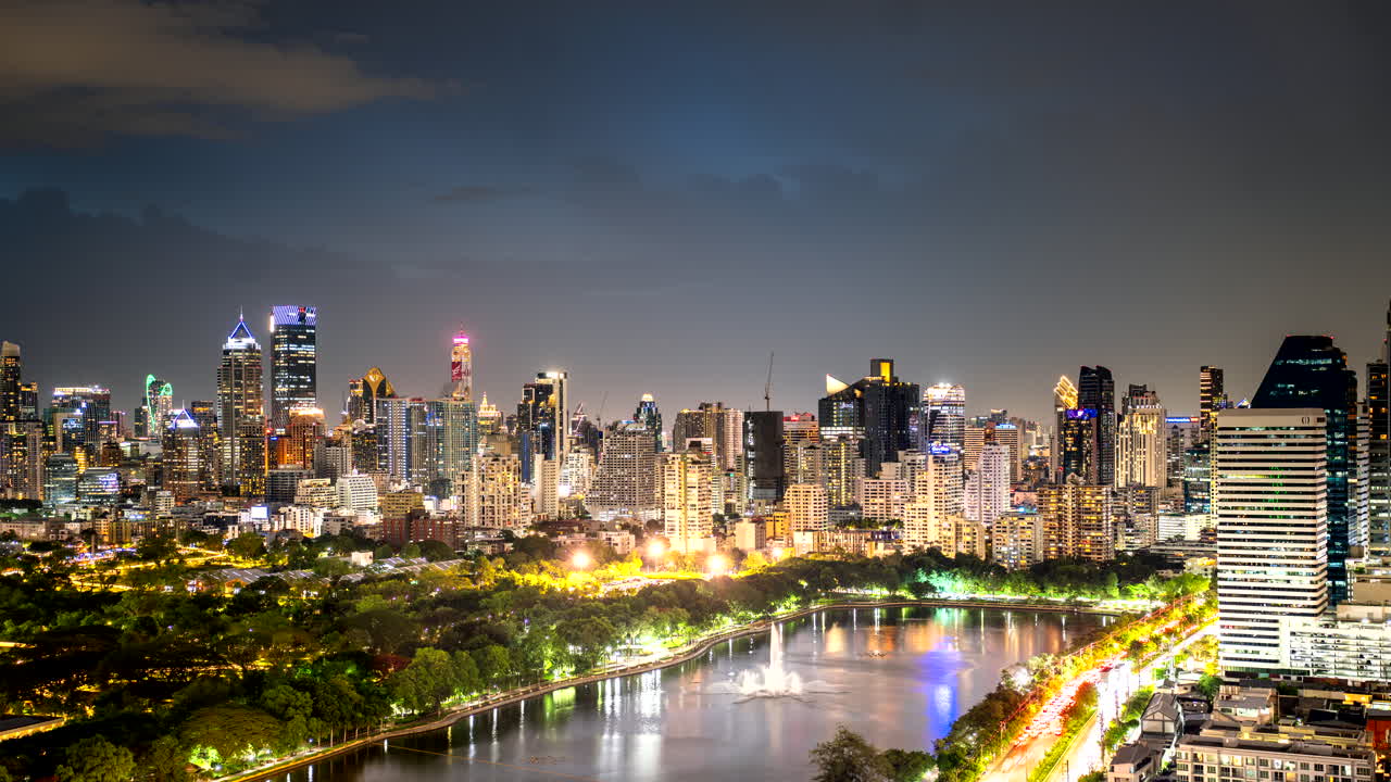 Timelapse of Benchakiti Park in Bangkok, Thailand, with modern skyline and evening lights reflected and sparkling in the water