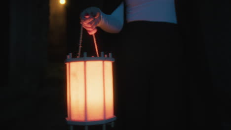 hand of young woman walking with lantern in hand through the streets of the city