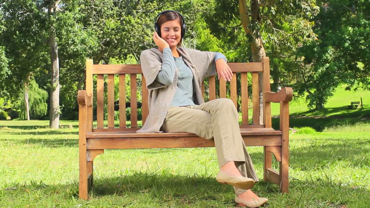 벤치 에서 음악 을 듣고 있는 젊은 여자