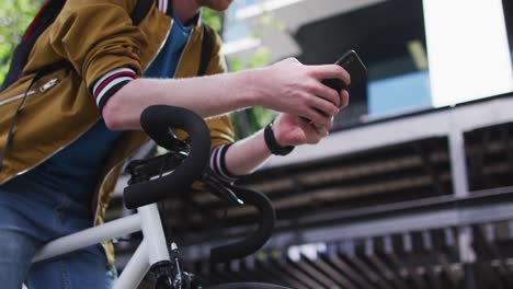 Happy-albino-african-american-man-with-dreadlocks-on-bike-using-smartphone