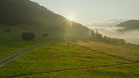 A-young-woman-walks-in-a-foggy-field-near-Wagenbrüchsee,-Germany-on-a-sunny-morning