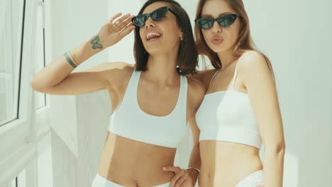 two women friends posing in white tops and sunglasses