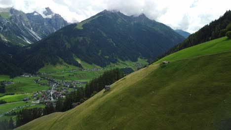 Drohne-Luftaufnahme-Der-Wiese-Mit-Hohen-Bergen-Im-Hintergrund,-In-Der-Nähe-Von-Vergoer---Einem-Kleinen-Dorf-Im-Stubaital-In-österreich