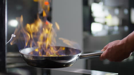 chef flambeing vegetables in skillet