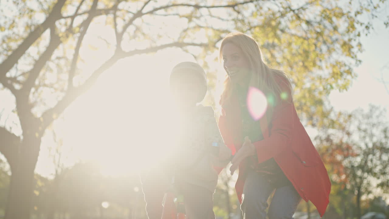 Mother helping child ride bike in the park