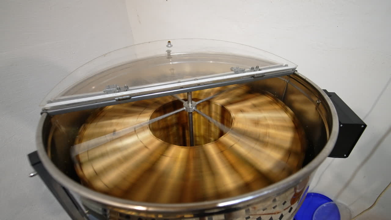 Electric machine for honey extraction working in the apiary. Device for harvesting fresh organic product at modern bee farm.