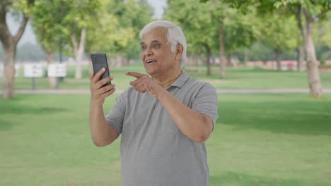 Happy-Indian-old-man-talking-on-video-call-in-park