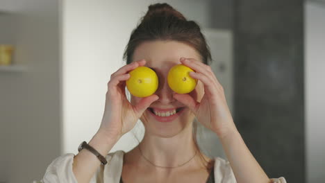 a smiling woman playfully holding lemons over her eyes