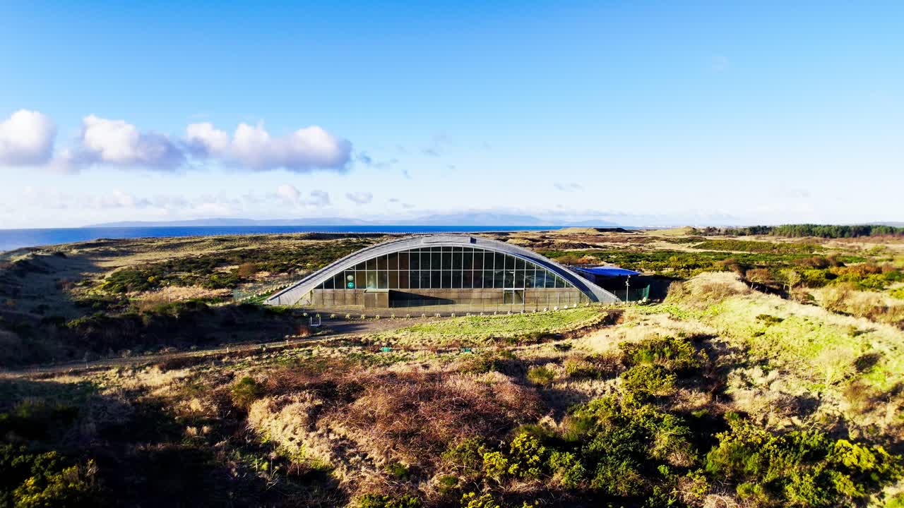 Vista aérea do abandonado centro de ciências Big Idea na Península de Ardeer, Irvine, North Ayrshire, Escócia, mostrando um marco moderno abandonado em meio a arbustos costeiros