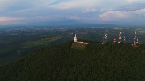 Drone orbiting right at La Cumbre, Colima, capturing the sunset with Colima city in the distance, panoramic establishing