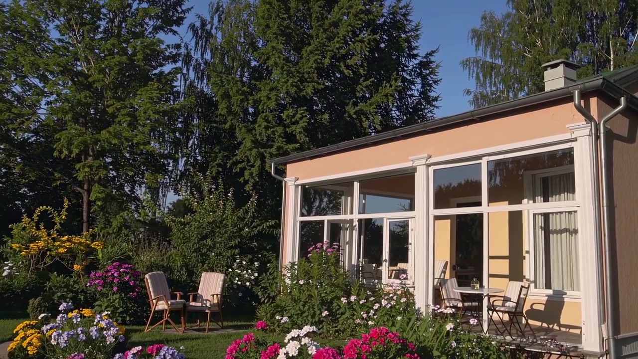 Vackert hus med uterum och livfull blomsterträdgård en solig dag