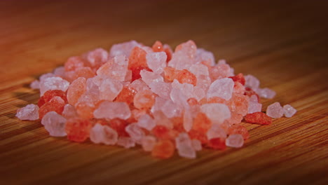 a pile of pink himalayan rose salt on a wooden surface with dramatic lighting, camera orbiting