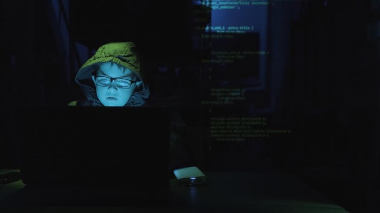 Geniale ragazzo hacker che lavora al computer portatile al buio con codici di programmazione sovrapposti. Zoomata.