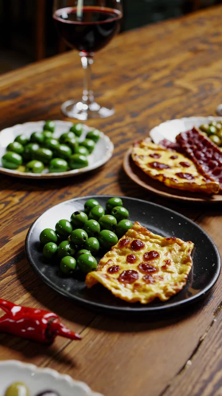 Aerial view of a rustic table with olives and pizza slices, styled for a cozy dinner video